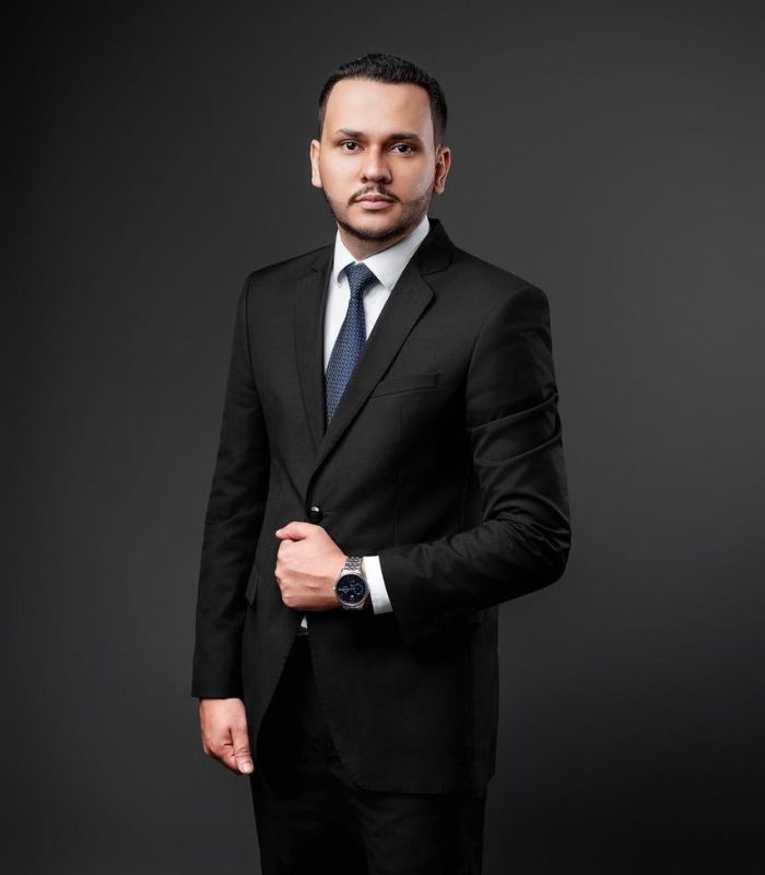 Retrato profissional de advogado criminalista, terno escuro, postura confiante, fundo com tons de azul petróleo e dourado, iluminação de estúdio dramática, fotografia realista